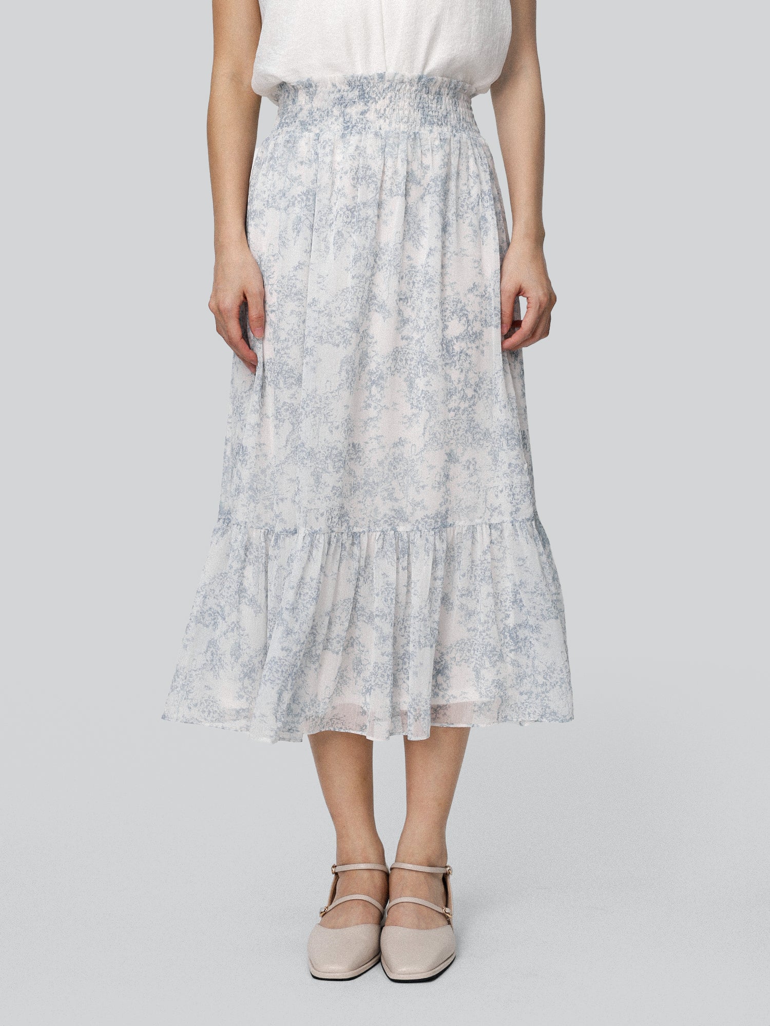A midi length skirt with smocking at the waist, featuring a floral pattern and a ruffled hem.